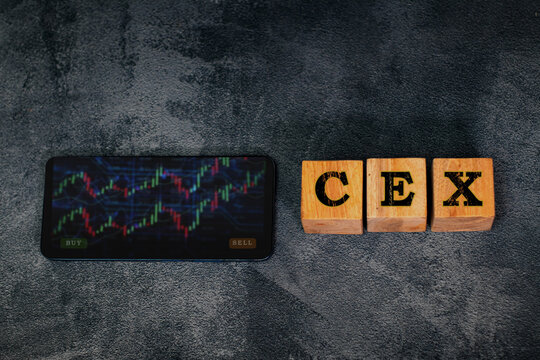 Wooden blocks forming the word &ldquo;CEX&rdquo; are placed beside a smartphone displaying colorful trading charts, representing centralized crypto exchanges, digital assets, and financial market concepts.