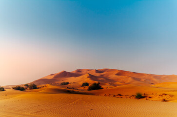 The sun rising on the pristine and untouched red dunes in the desert near Dubai