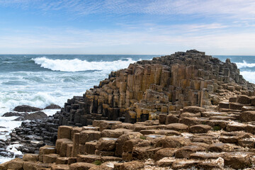 Basalt columns caused by ancient volcanic fissure eruption along the The Giant's Causeway coastline near Bushmills, Northern Ireland with waves crashing against the rocks during storm