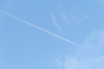 Line-shaped clouds called contrails or vapour trails in blue sky produced by aircraft engine exhaust at aircraft cruising altitudes several kilometres above the earth's surface