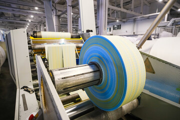 A large production machine with a large spool of white fabric, which are used in textile production.