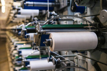 There are many large spools of white thread on the shelves, which are used in textile production