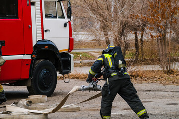 Firefighters in protective suits and masks with breathing apparatus, against the background of a...