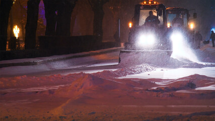 Large snow tractor at work on the evening streets of the city