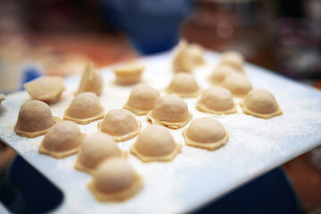 Homemade hexagonal dumplings on white plastic board before boiling in water