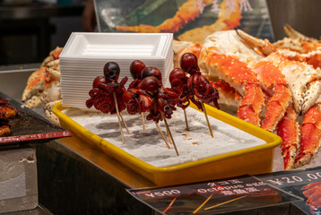 Stalls sell octopus snacks and crab dishes at a food market in Japan during evening hours