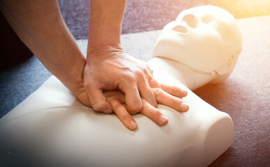 CPR first aid training demonstration - Cardiopulmonary emergency resuscitation medical procedure on dummy. Teaching chest compression technique to students learning via mannequin doll.