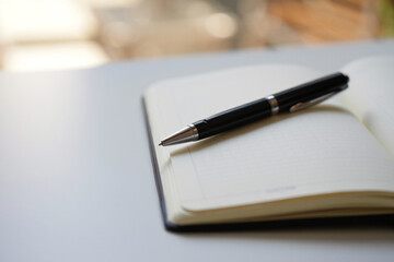 Black Ballpoint Pen Resting on Open Notebook Surface Close Up Elegant Writing Tool for Journaling Taking Notes Office Desk Stationary