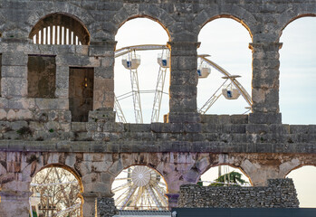 Close-up of the Ferris wheel seen through the stone arches of the ancient Pula Arena