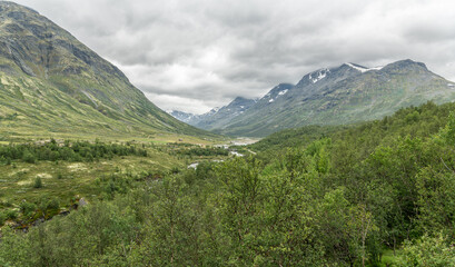 Obraz premium View from Vegaskjelet viewpoint on norwegian valley with mountains, 2000 metre peaks of Skarsnebb and Steinetind in Jotumheimen.. Amazing viewpoint on beautiful nature, wilderness.