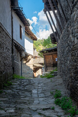 A narrow stone street between old, historic houses in the village of Kovachevitsa in the Rhodope Mountains, Bulgaria