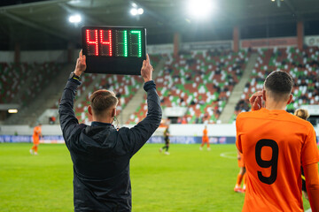 Technical referee shows players substitution during football match.