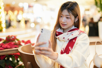 Smiling young woman on Christmas video call looking at her phone during the holiday season