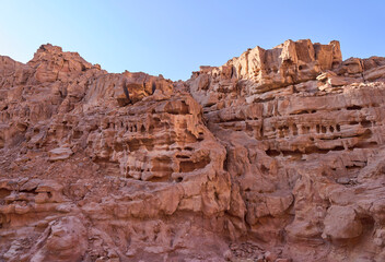Bizarre stone structures and tracery, created by the nature, in Eilat Mountains nature reserve. Colorful pattern created by the nature on a rock wall. Colorful sandstone. Red rocky mountains.