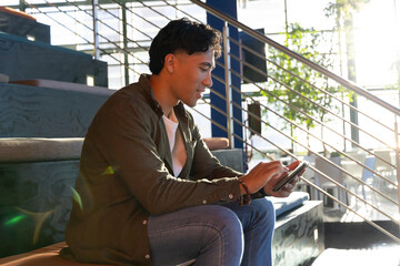 Man sitting on wooden bench steps in modern lounge area interacting with touchscreen tablet