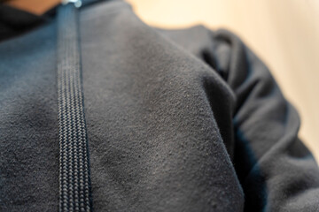 A close-up view of a black hoodie with a zipper, showcasing the texture and material details. The soft fabric highlights comfort and casual style, ideal for fashion or lifestyle contexts.