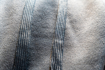 Close-up of a textured grey fabric displaying two parallel drawstrings. The detail showcases the material's softness and weaving, highlighting its use in casual clothing or sportswear.