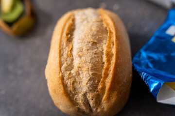 Close-up of a fresh, golden bread roll on a dark surface, perfect for adding visual appeal to food-related projects and culinary art. Ideal for use in advertisements.