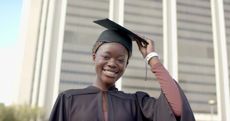 At clip start African American woman outside building raising cap onto head securing tassel