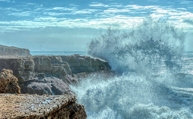 THE FORCE OF THE WAVES BREAKING ON THE ROCKS OF CAPE CERVERA HUERTA, LA MATA BEACH, ALICANTE, SPAIN