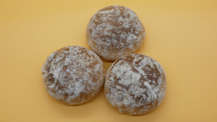 Sweet dessert balls with powdered sugar on a yellow background