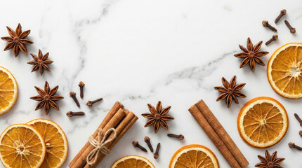 Arrangement of aromatic holiday spices like cinnamon sticks star anise and dried orange slices on white marble for festive baking or winter recipes