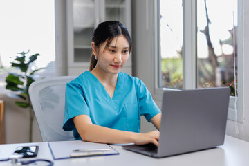 Asian nurse or doctor providing online medical consultation, using a laptop for telehealth services in a modern clinic office