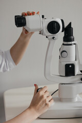 Naklejka premium Hands adjusting ophthalmic microscope during eye inspection in medical clinic