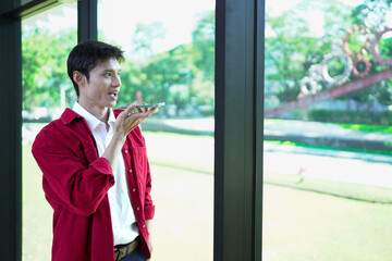 A young man is using a voice command or communicating with an artificial intelligence assistant on his smartphone