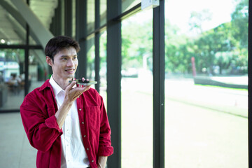 A young man is using a voice command or communicating with an artificial intelligence assistant on his smartphone