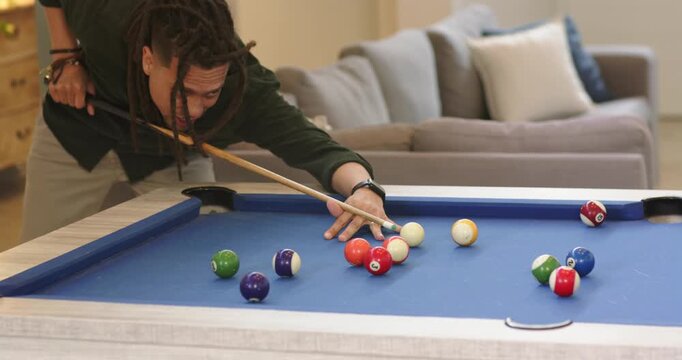After cue tip aligning behind rack, pool player drawing back, breaking balls across blue-felt table