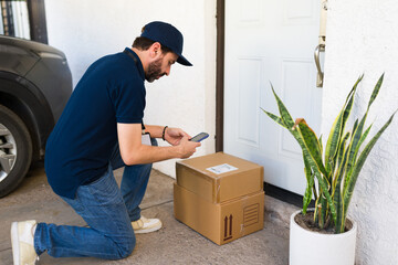 Delivery man scanning package barcode with smartphone on front door doorstep, confirming safe parcel arrival