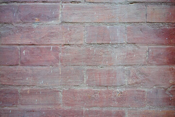 Close-up of a red brick wall with weathered texture and small white paint marks