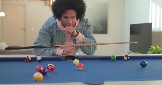 Man leaning over pool table at home studying balls, chalking cue for precise shot before striking