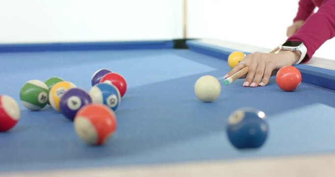 Female friends breaking rack on pool table at home after placing cue ball to start game