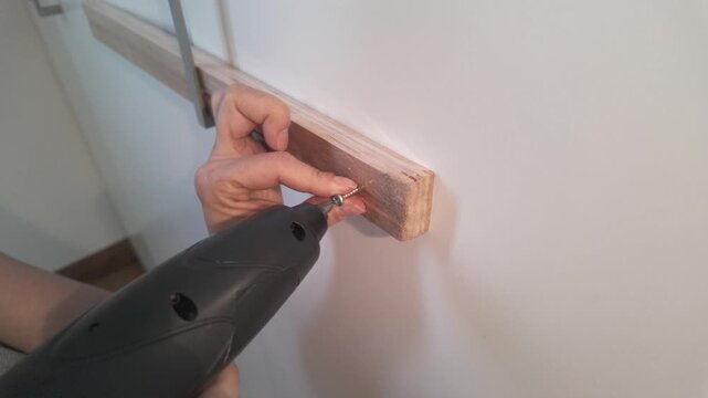 Side view of electric screwdriver driving screw into wood panel