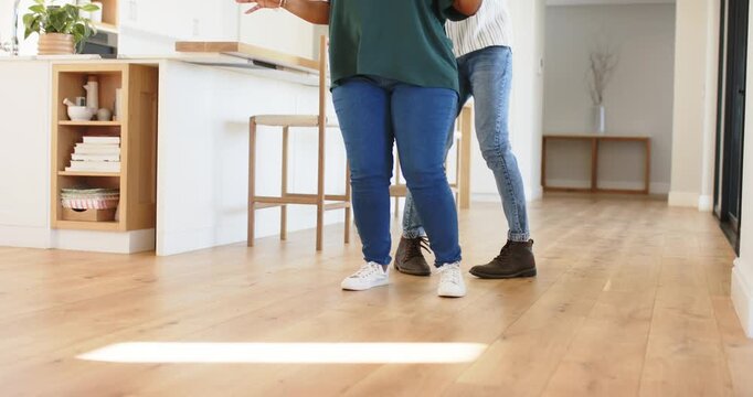 At setup male female dance partners practicing side to side stepping across floor by kitchen island