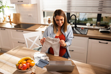 Pregnant Woman Showing Baby Clothes