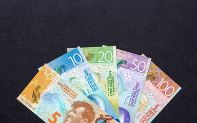 New Zealand money. All paper banknotes of the New Zealand currency dollar, arranged in a fan on a black background. Financial business NZD concept. Flat lay.  Copy space