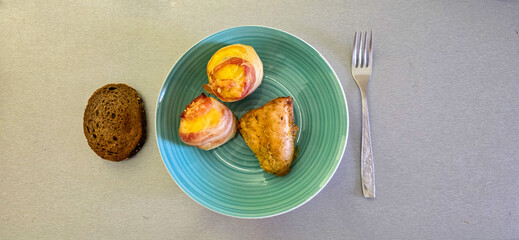 Turquoise plate arrangement: bacon-wrapped potatoes, chicken breast, cutlery