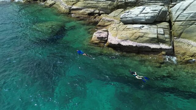 Vacation in Southeast Asia, sea trip in Thailand. Snorkeling near tropical islands. A couple of men in masks and fins explore the underwater world off Racha Yai Island.