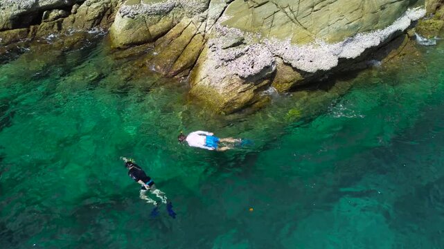 Vacation in Southeast Asia, sea trip in Thailand. Snorkeling near tropical islands. A couple of men in masks and fins explore the underwater world off Racha Yai Island.