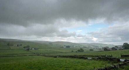 Dramatic green rolling countryside scene endures a gentle summer rain under moody clouds