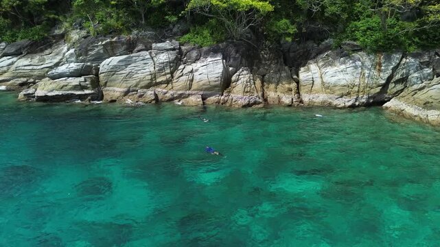 Vacation in Southeast Asia, sea travel in Thailand. Snorkeling near tropical islands. Tourists off the coast of Koh Racha Yai explore the underwater world, as seen from a drone.
