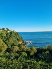 Picturesque emerald Basque coast along Bay of Biscay with rocky islands on shelf and piercing blue water of Bay of Biscay.  Biscay, Basque Country, Spain