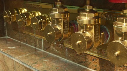 Brass standpipe connection under inspection, closeup of service panel, threaded caps, valve stems, industrial lighting, routine maintenance context, safety signage hint, urban building infrastructure