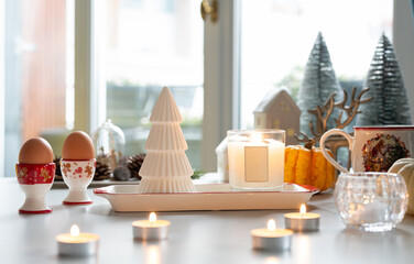 A Christmas decoration atmosphere with candle light, egg cup and mini Christmas tree in background.