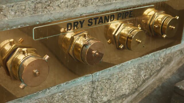 Heritage brass standpipe exterior detail, architectural conservation of brass fittings on historic building facade, exterior view of aged brass standpipe fittings with stone surround on heritage