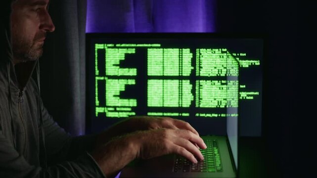 Silent hacker at work, Quiet programmer monitoring illuminated code, Stealthy software developer engaged with glowing display, Shadowy coder concentrating on luminous digital interface in darkness