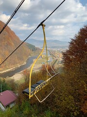 Autumn Chairlift Over Mountain River Valley in Ukraine; open-air chairlift glides above a colorful autumn landscape in the mountains of Ukraine